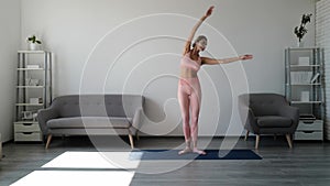 Young beautiful woman in sportswear doing stretching on yoga mat at morning. Fitness and exercise at home. Healthy life