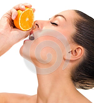 Young beautiful woman squeezes orange on white bacground