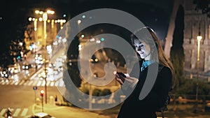 Young beautiful woman standing in the city centre near the Colosseum in Rome, Italy and using the smartphone.