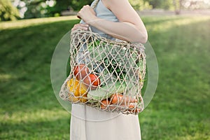 Young beautiful woman standing with ecological zero waste shopping bag with vegetables