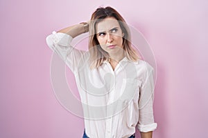 Young beautiful woman standing over pink background confuse and wondering about question