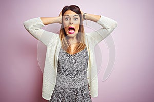Young beautiful woman standing over pink isolated background Crazy and scared with hands on head, afraid and surprised of shock