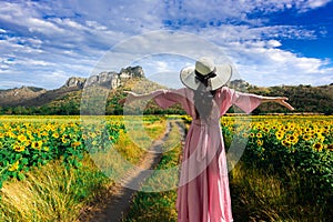 Young beautiful woman stands with her back turned on a blurred background with a field of sunflowers at Lopburi,Thailand