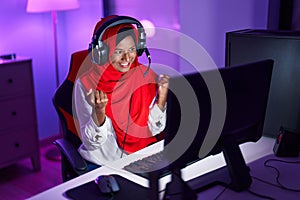 Young beautiful woman streamer playing video game with winner expression at gaming room