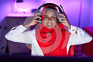 Young beautiful woman streamer smiling confident wearing headphones at gaming room