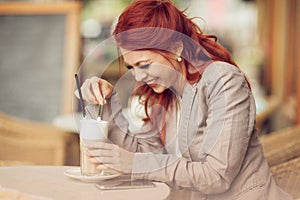 Young beautiful woman in a street cafe enjoying a coffee, summerly urban mood