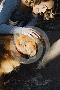 Young beautiful woman stroking a dog and smiling