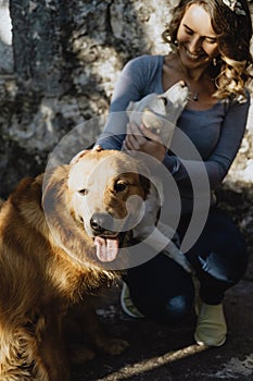 Young beautiful woman stroking two dogs and smiling