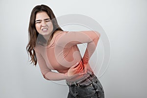 Young beautiful woman suffering from lower back pain looking helpless on isolated white background, healthcare concept