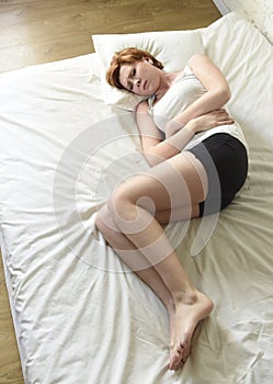 Young beautiful woman suffering stomach cramps on belly holding tummy with her hands in period pain