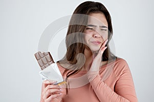 Young beautiful woman suffering toothache after eating chocolate bar looking miserable standing on isolated white background,