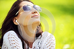 Young beautiful woman in summer park enjoy music