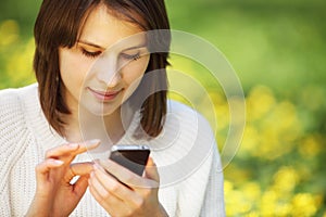 Young beautiful woman in summer park reading a message