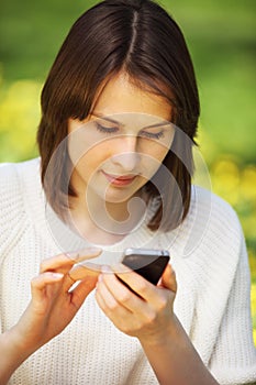 Young beautiful woman in summer park reading a message