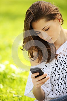 Young beautiful woman in summer park reading a message