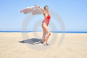 Young beautiful woman sunbathing with open arms holding towel at maspalomas dunes bech