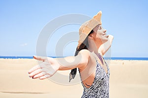 Young beautiful woman sunbathing with open arms wearing summer swinsuit at maspalomas dunes bech