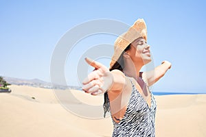 Young beautiful woman sunbathing with open arms wearing summer swinsuit at maspalomas dunes bech