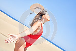 Young beautiful woman sunbathing with open arms wearing summer swinsuit at maspalomas dunes bech