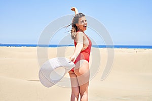 Young beautiful woman sunbathing with open arms wearing summer swinsuit at maspalomas dunes bech