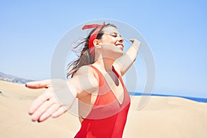 Young beautiful woman sunbathing with open arms wearing summer swinsuit at maspalomas dunes bech