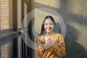 Young beautiful woman in sunshine light enjoying her morning coffee at home.Young beautiful woman in sunshine light enjoying her