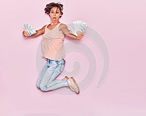 Young beautiful woman surprised holding dollars banknotes 