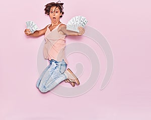 Young beautiful woman surprised holding dollars banknotes 