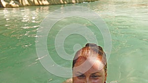 Young beautiful woman swimming in lake with blue water