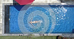 The young beautiful woman swims in the pool, flat lay, dron view