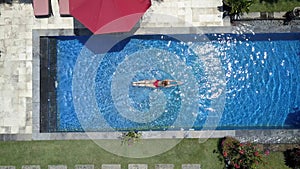 Young beautiful woman swims in the pool, flat lay, dron view.