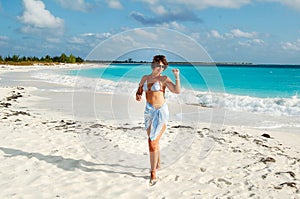 Young beautiful woman in a swimsuit on the sea beach. Sea vacation concept. The girl enjoys the coolness of the sea