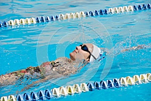 Young beautiful woman with swimsuit swimming on a blue water pool