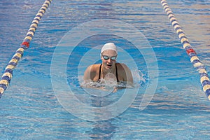 Young beautiful woman with swimsuit swimming on a blue water pool