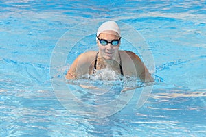 Young beautiful woman with swimsuit swimming on a blue water pool