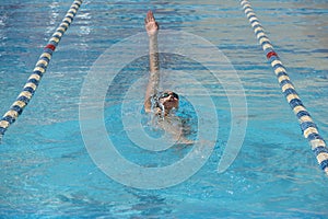 Young beautiful woman with swimsuit swimming on a blue water pool