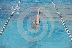 Young beautiful woman with swimsuit swimming on a blue water pool