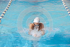 Young beautiful woman with swimsuit swimming on a blue water pool