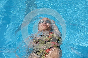 Young beautiful woman with swimsuit swimming on a blue water pool