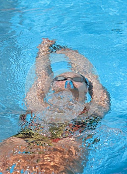 Young beautiful woman with swimsuit swimming on a blue water pool