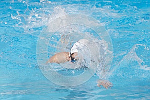 Young beautiful woman with swimsuit swimming on a blue water pool