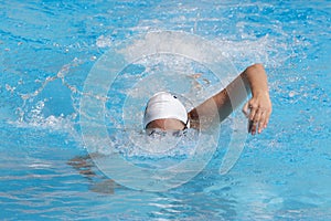 Young beautiful woman with swimsuit swimming on a blue water pool