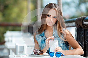 Young beautiful woman at a table in summer cafe