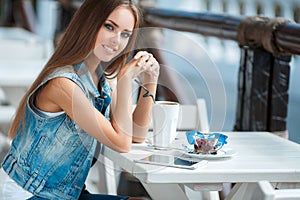 Young beautiful woman at a table in summer cafe