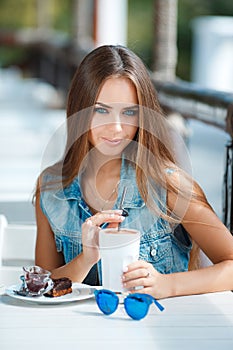 Young beautiful woman at a table in summer cafe