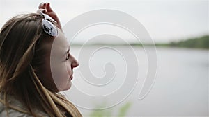 Young beautiful woman is taking off the sunglasses and enjoying a spring lake landscape.