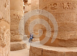 Young beautiful woman taking pictures between the columns of the hypostyle hall of Karnak's temple in Luxor, Egypt