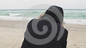 Young beautiful woman taking pictures of the sea on a cold winter day. Slow motion