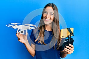 Young beautiful woman taking a selfie photo with smartphone flying drone smiling with a happy and cool smile on face