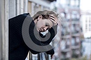 Young beautiful woman thinking and feeling sad suffering depression at urban city background home balcony